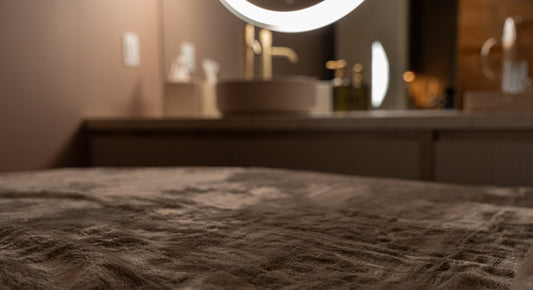Closeup image of AMAN Spa's massage bed with a soft velvet blanket and a blurry background in sim lighting